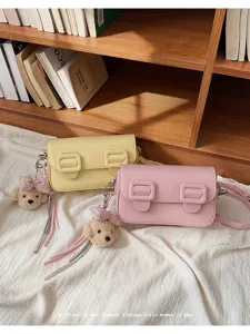 Close-up of vintage style shoulder bags with cute bear keychains and double buckle details.