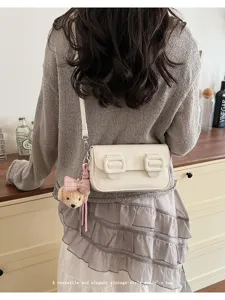 Vintage style women's shoulder bag with cute bear pendant, elegant cross body bag detail.
