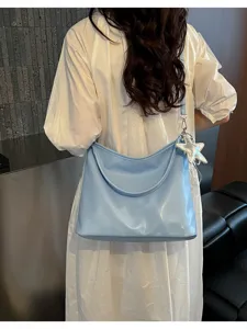 Light blue slouchy shoulder bag detail view, casual daily tote purse with silver star pendant.