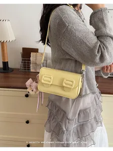 Detail view of the elegant vintage-style yellow shoulder bag with double buckle design.