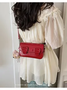 Red patent leather crossbody bag detail, vintage style small square purse with cute bear charm.