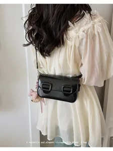 Detailed view of a vintage style black leather crossbody small square bag with bear charm.