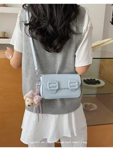 Vintage light blue crossbody bag with cute bear pendant and double buckle design.