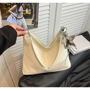 Detailed view of cream white leather shoulder tote bag with shiny star charm and silver hardware.