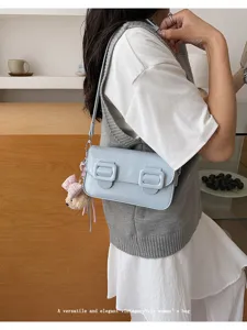 Detail shot of light blue vintage shoulder bag with double buckles and cute bear pendant.
