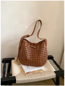 Gedetailleerd overzicht van de bruine geweven hobo bucket bag met fijne opengewerkte textuur.