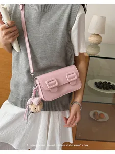 Trendy pink PU leather shoulder cross-body bag featuring double buckles and cute bear charm.