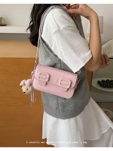 Pink vintage shoulder bag detail with double buckles and cute bear charm. Elegant and chic style.