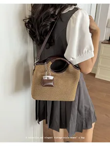 Detailed view of the woven straw bucket bag with leather trim and chic miniature lock charm.