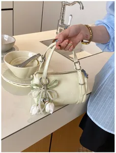 Detail shot of the cream cylindrical pillow bag featuring a pearl tulip charm and design.