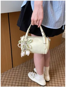 Chic light yellow cylindrical pillow bag for women, stylish barrel shoulder bag with pearl pendant.