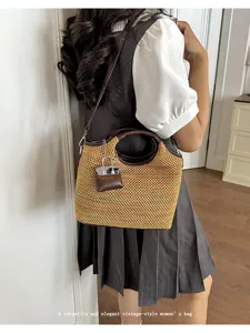 Detailed view of the woven bucket handbag with leather handle and mini charm pendant.