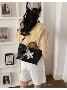 Details of women's black star pattern tote bag with shoulder strap and star charm accessory.