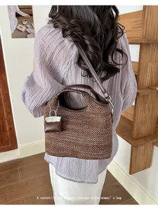 Detailed back view of a stylish woven bucket handbag with mini charm and shoulder strap.