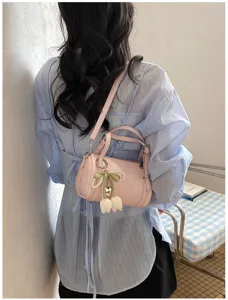 Detail view of stylish pink pillow shoulder bag with cute pearl tulip charm and sleek design.