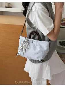 Charming star print tote bag detail featuring a stylish silver star pendant and brown handles.