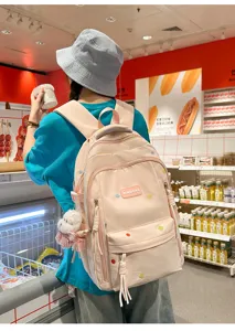 Detailansicht des rosa Studentenrucksacks mit süßem Plüschanhänger und bunten Stickereien.