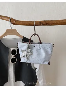 Casual star print tote bag with stylish contrast handle and cute star pendant accessory.