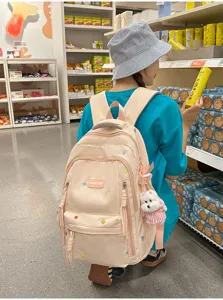 Detailansicht eines großen rosafarbenen Schulrucksacks mit niedlichem Anhänger für Schüler.
