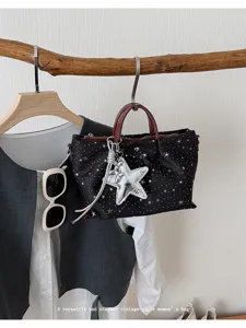Black star print canvas handbag with silver star pendant and brown handles for daily use.
