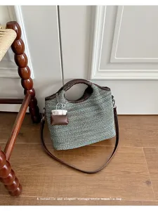 Woven bucket shoulder bag with brown leather handles and chic miniature charm accessory.