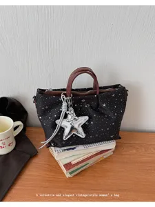 Detail view of a stylish black star print tote bag with brown handles and silver balloon pendant.