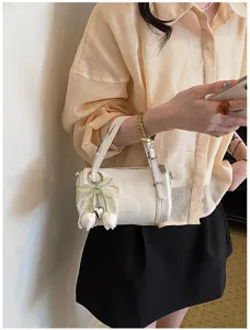 Chic white small pillow shoulder bag detail, elegant pearl tulip pendant, stylish everyday look.