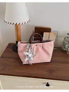 Detailed view of the pink star-print tote bag with silver star charm and brown leather handles.