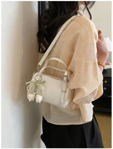 Stylish minimalist white pillow shoulder bag for women, chic crossbody bag with cute charm.