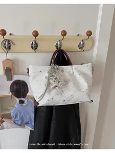 Detail view of the stylish white star print tote bag hanging on a hook, fashion women shoulder bag.