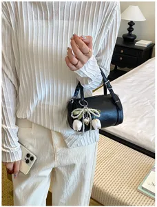 Minimalist black pillow shoulder bag with chic pearl tulip charm detail, stylish daily accessory.
