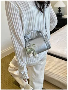 Detail view of the silver metallic pillow crossbody bag with cute pearl tulip pendant and strap.