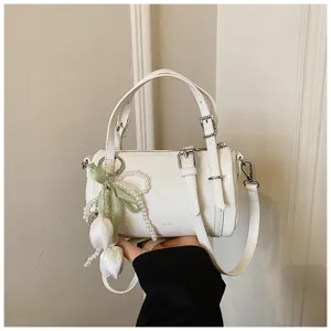 White cylindrical shoulder bag for women, featuring a chic pearl tulip pendant and strap.
