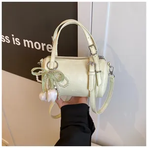 Chic light yellow cylindrical pillow shoulder bag with pearl tulip charm and buckle straps.