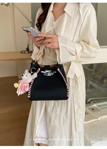 Chic contrast color bucket handbag with knitted bear pendant and metal turn-lock closure.