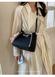 Close-up detail of women's black shoulder bucket bag with pink braided edges and lock.