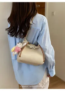 Stylish leather shoulder bag with whipstitch trim and cute bear pendant for daily commute.
