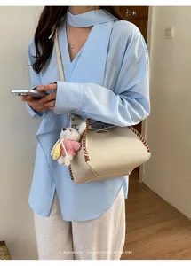 Stylish women's leather crossbody bag with contrast woven edges and chic knitted doll pendant.