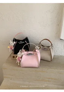 Detailed view of women contrast texture woven bucket bag with cute charm pendant retro style.