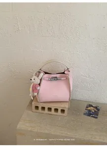 Chic pink leather bucket bag with woven details top handle and cute bunny pendant for women.