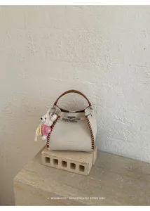 Detailed view of the stylish leather bucket bag with contrast stitching and cute bear charm.