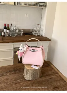 Detailed shot of pink leather bucket bag with woven edges and cute rabbit pendant charm.