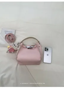 Pink textured leather handbag detail featuring stylish side whipstitching and metallic turn-lock.