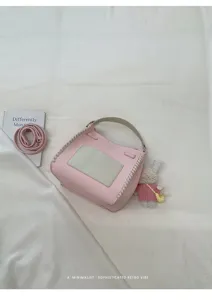 Detailed shot of pink textured woven crossbody bag with contrasting white panel and cute rabbit doll.