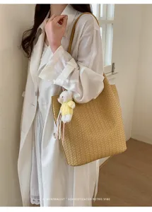 Chic Korean style woven leather shoulder tote bag with cute bear pendant for daily commute.