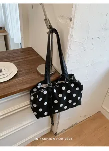 Detail view of a stylish black and white polka dot canvas shoulder bag hanging on a lamp.