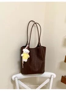 Minimalist woven leather tote bag with cute bear pendant for daily commuting and fashion.