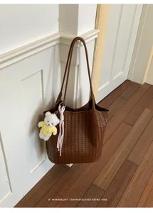 Detailed shot of Korean style brown woven leather bucket bag with cute bear charm hanging.