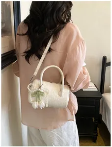 Detail shot of white textured barrel shoulder bag with pearl tulip pendant for chic commuting.
