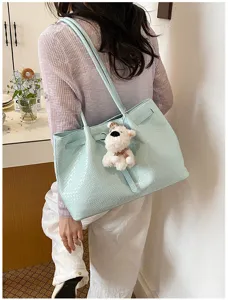Close-up view of a light blue woven tote bag with cute bear keychain for women's daily commute.